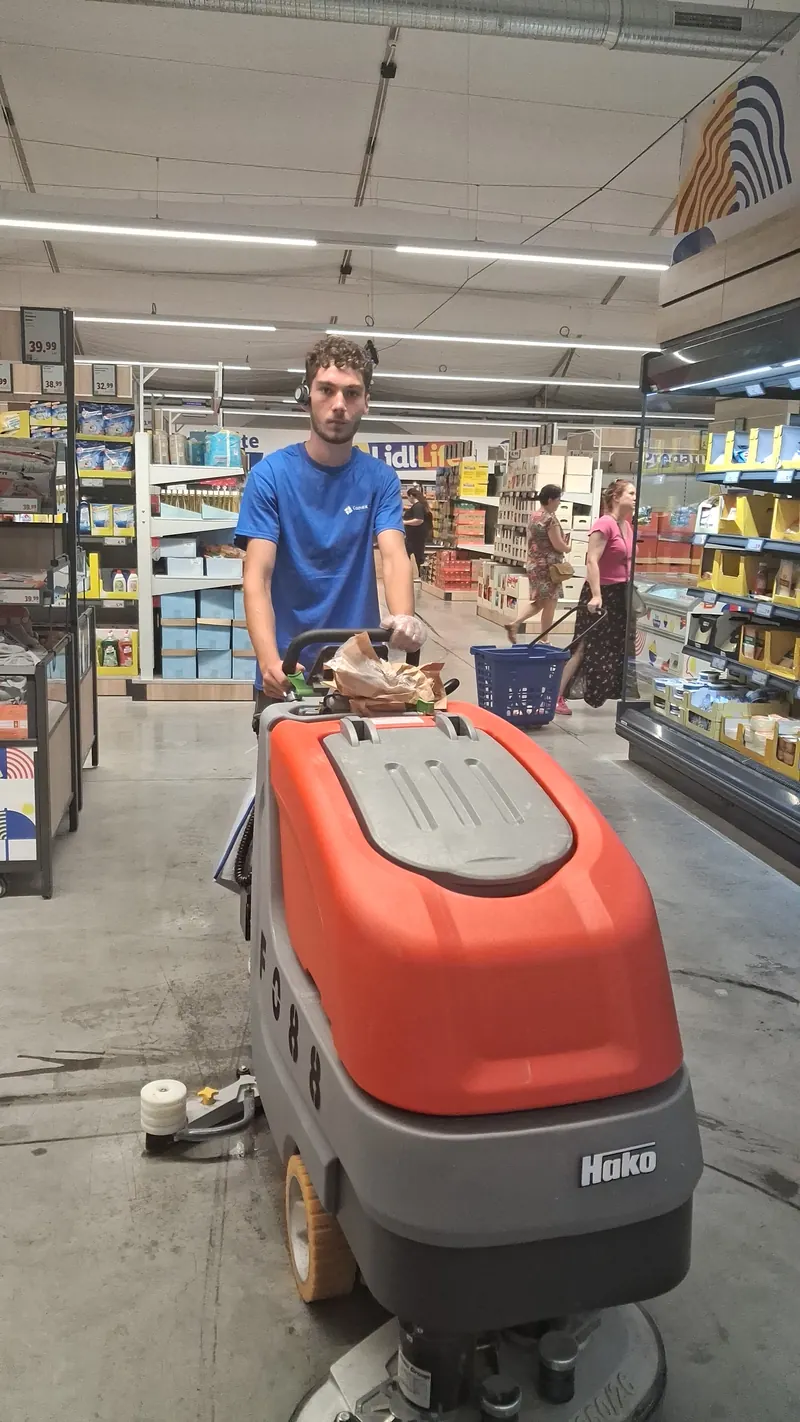 Operator cu mașina de spălat pardoseli într-un supermarket